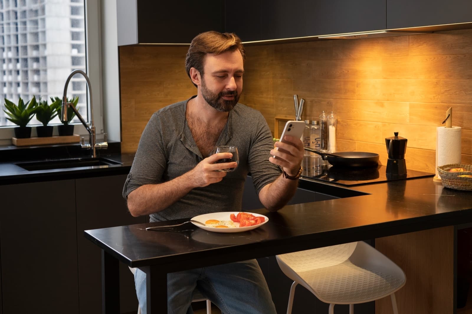 A man checking his phone over breakfast at a kitchen counter